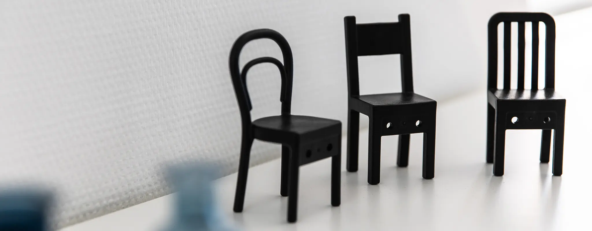 Drei schwarze Miniaturstühle auf einem weißen Regal