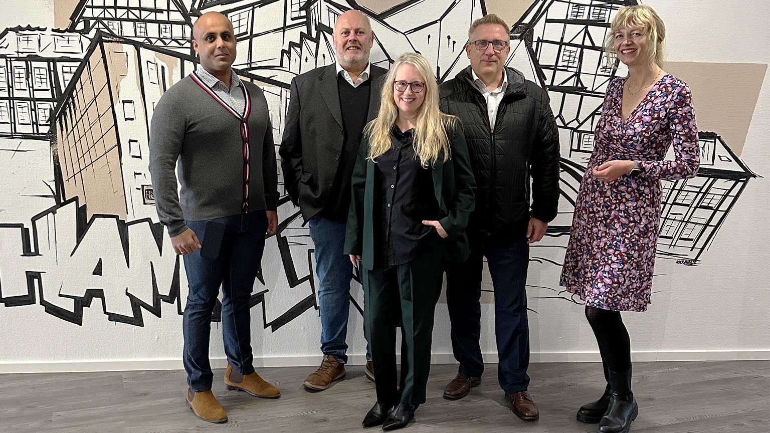 Projektgruppe des Business Welcome Center vor einer Graffiti Wand mit der Stadt Hameln