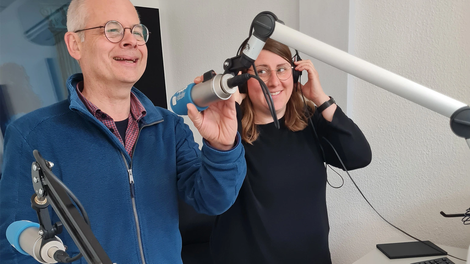 Lächelnde Dozenten im Senderaum eines Radiosenders am Mikrofon