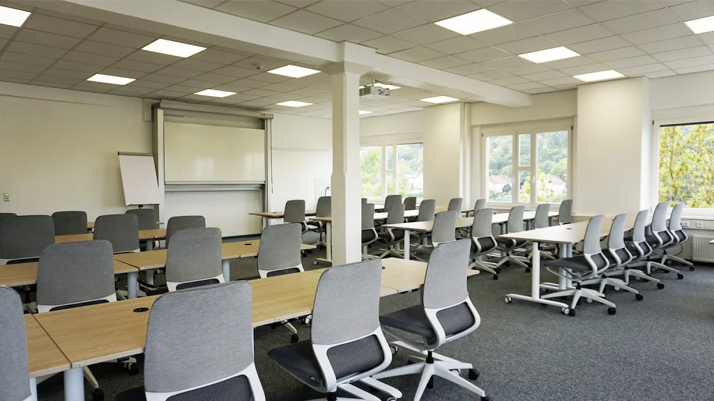 Seminarraum mit Stuhlreihen und Blick nach vorne zum Whiteboard und Flipchart