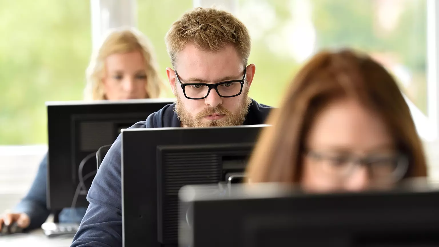 Studierende arbeitend sitzend an Tischen an Computern