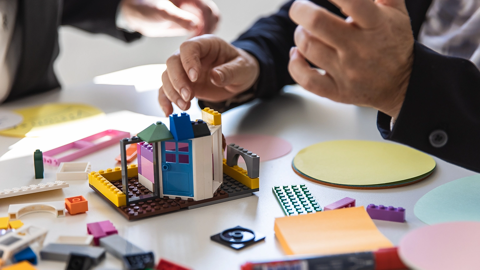 Hand baut auf einem Tisch etwas mit Lego