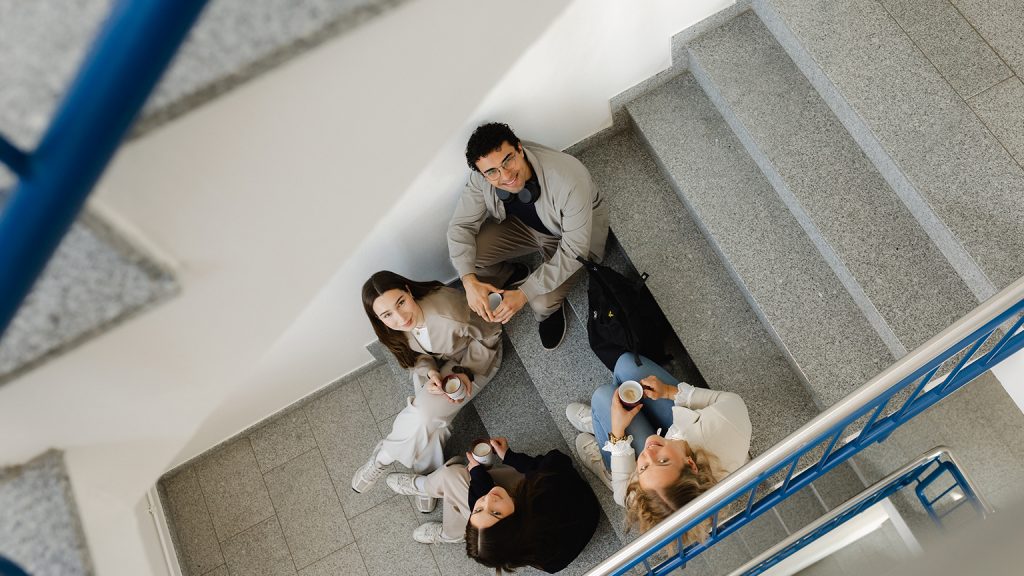 Studierende sitzen auf einer Treppe. Man sieht sie von oben.