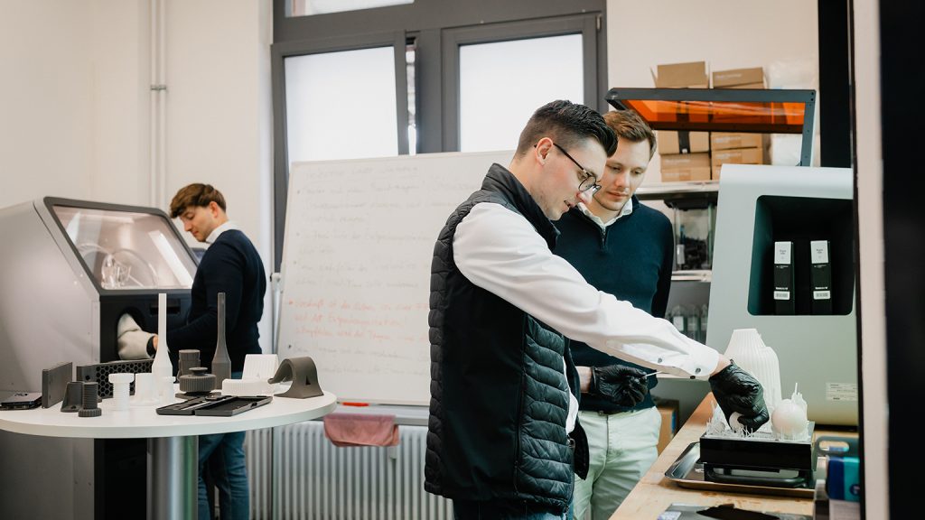 Zwei Männer arbeiten an einer 3-D-Druckmaschine.